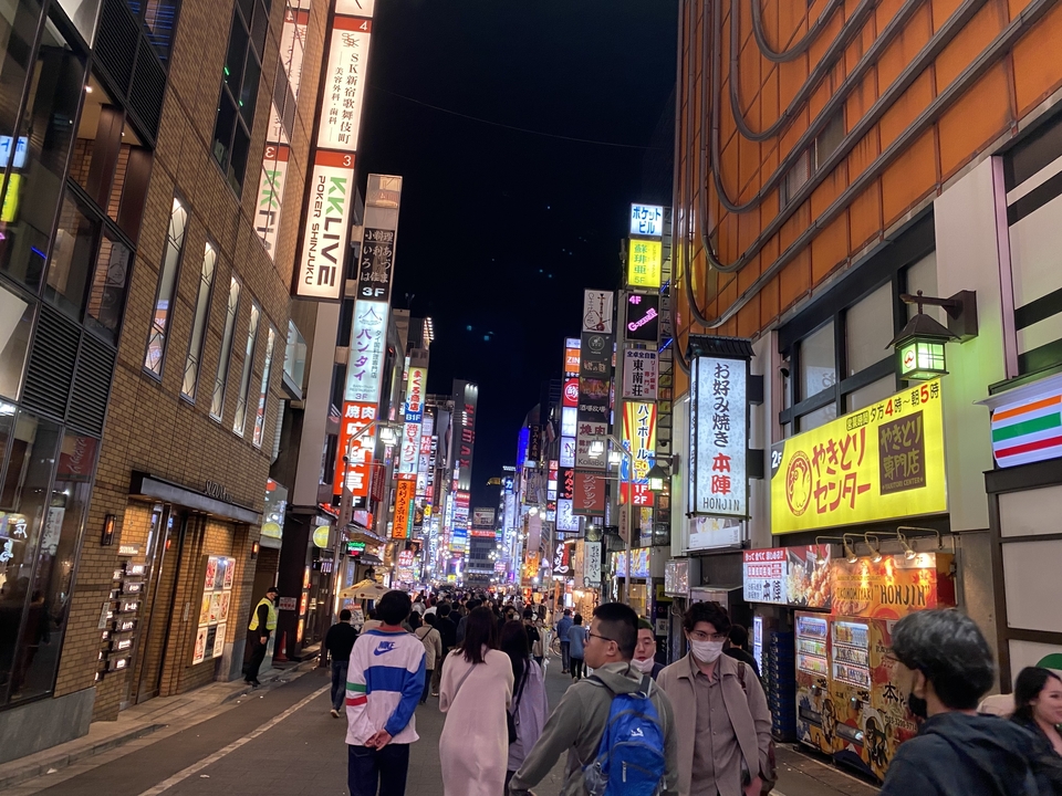 Bustling street at night illuminated with vibrant signs and lights.