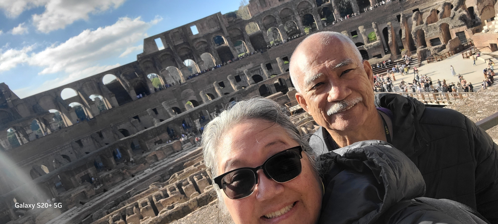 Deux personnes prennent un selfie à l'intérieur d'un grand amphithéâtre antique.