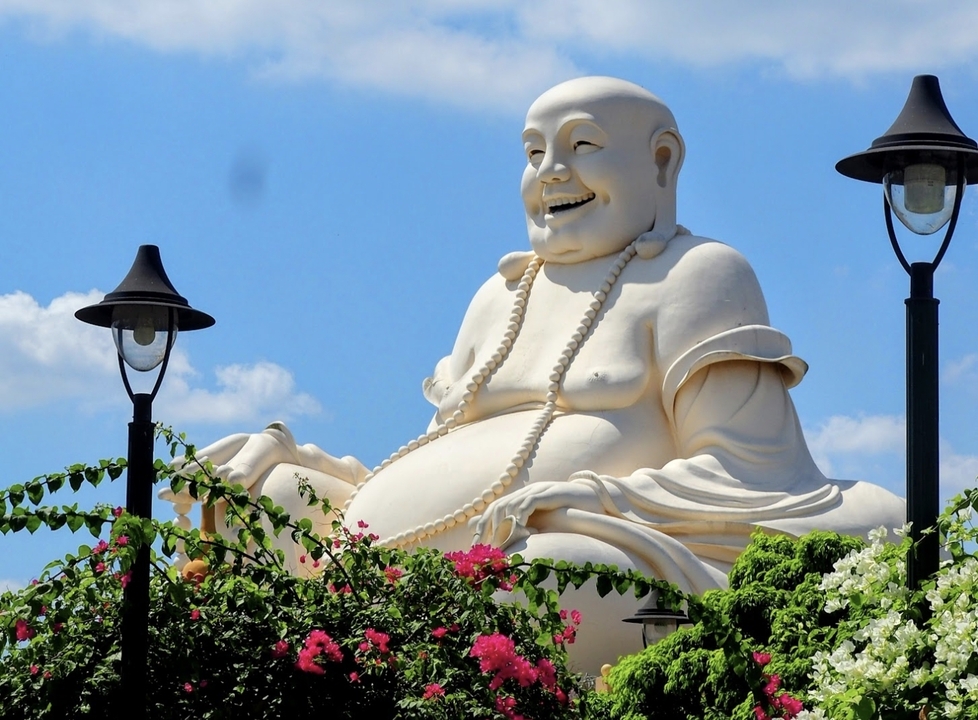 Grande statue d'un Bouddha entourée de fleurs.