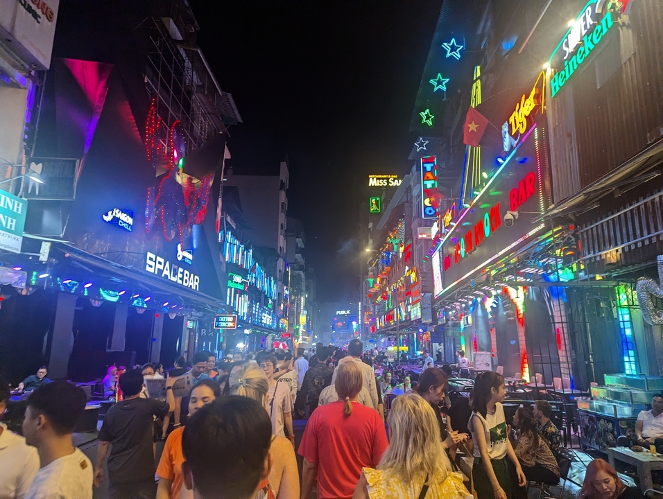 Scène de vie nocturne animée avec des enseignes lumineuses.