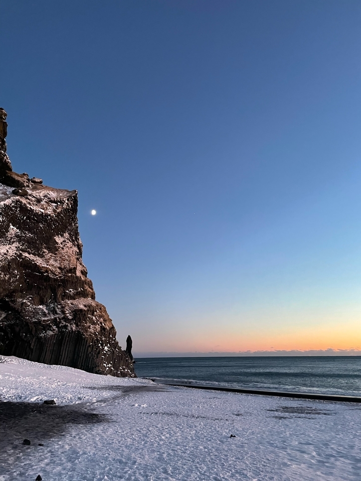 Snowy cliff with the moon in the sky.