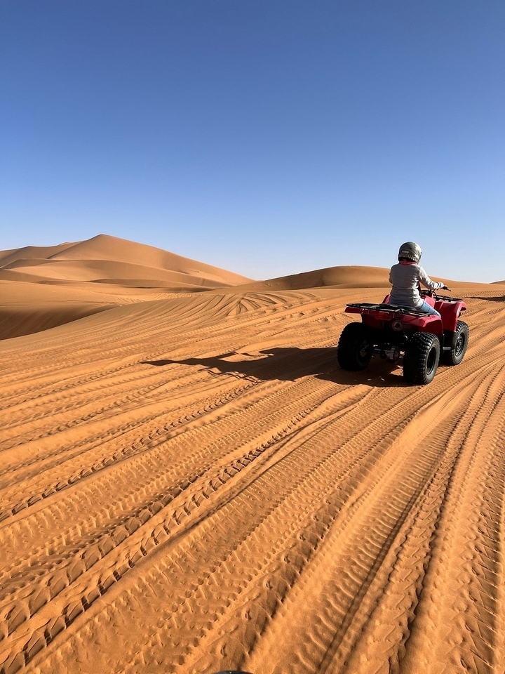 Personne conduisant un VTT sur des dunes de sable.