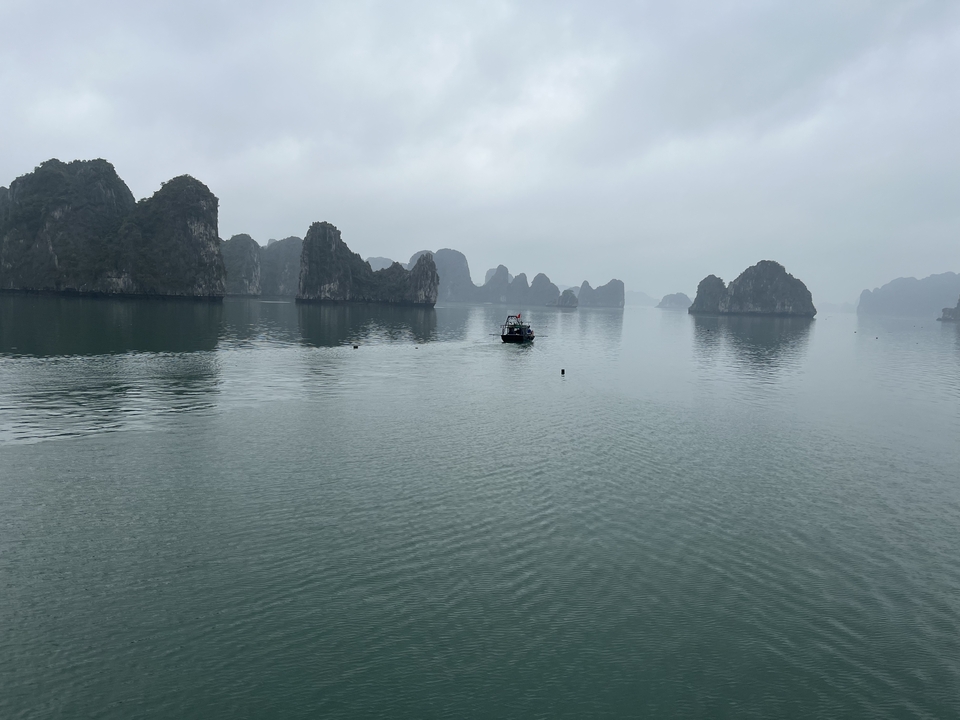 Bateau naviguant entre les îles calcaires par une journée brumeuse.