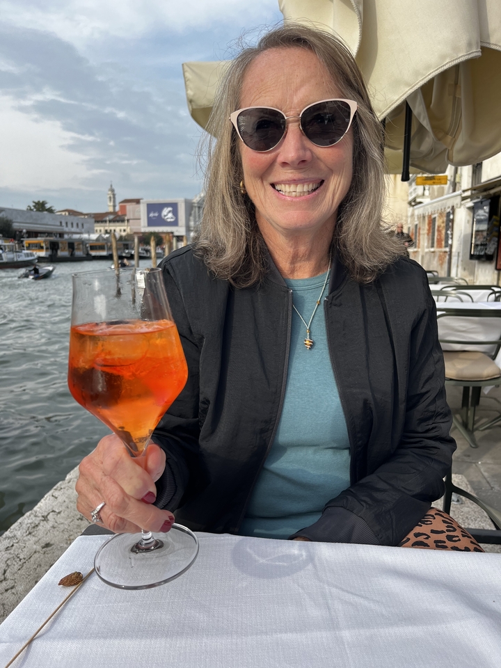 Personne tenant une boisson au bord d'un canal avec des bateaux.