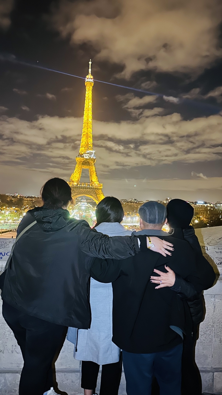 Quatre personnes regardant la Tour Eiffel illuminée la nuit.