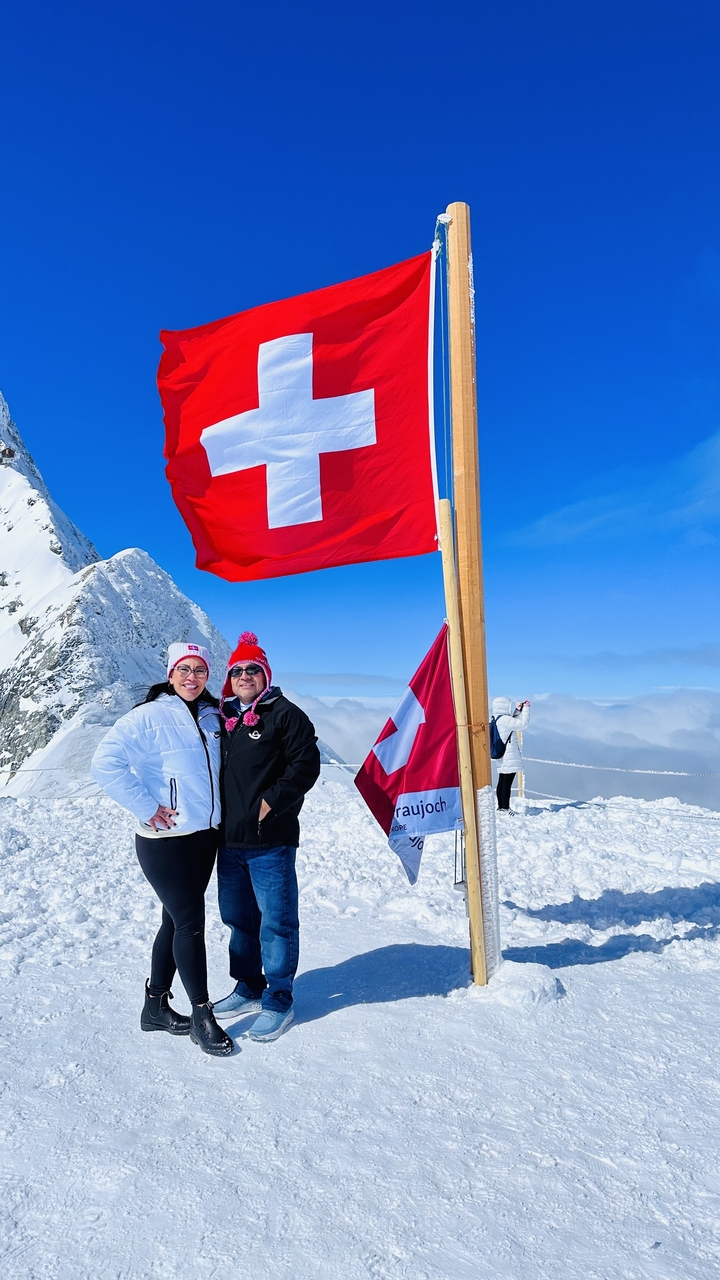 Deux personnes posant dans un paysage enneigé avec un drapeau suisse.