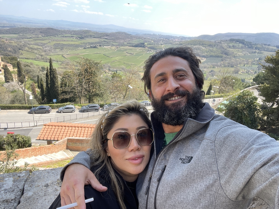 Couple posant avec un paysage de campagne pittoresque en arrière-plan.