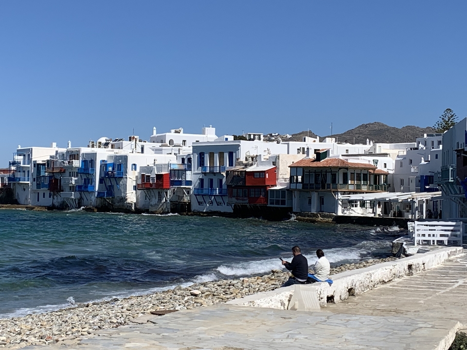 Village côtier avec des bâtiments blancs et des gens assis au bord de l'eau.