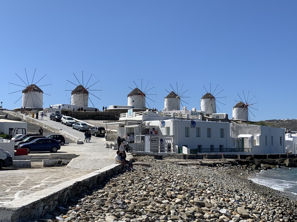 Rangée de moulins à vent traditionnels au bord de la mer avec des touristes.