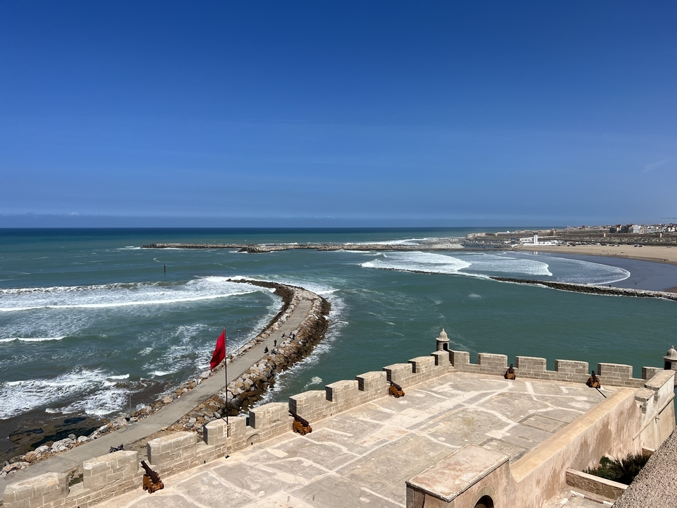 Vue côtière avec vagues et jetée rocheuse.
