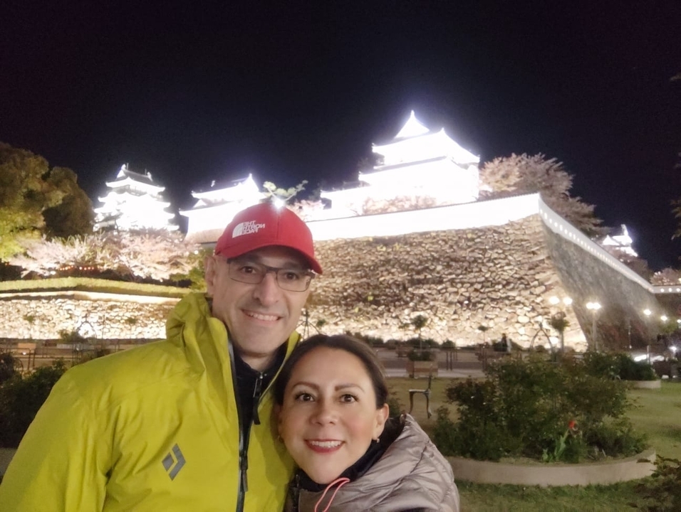 Un couple qui pose la nuit devant un château illuminé.