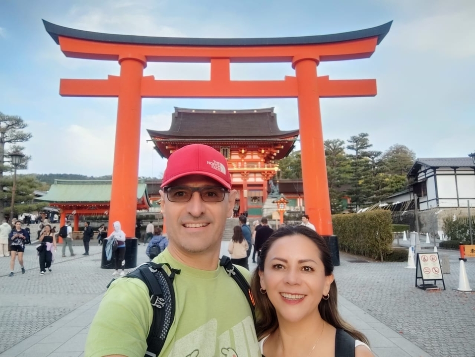 Un couple posant devant un torii rouge dans un sanctuaire.