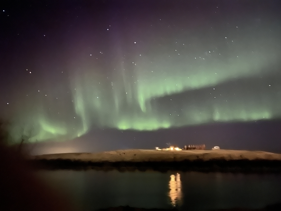 Northern lights over a hilly landscape