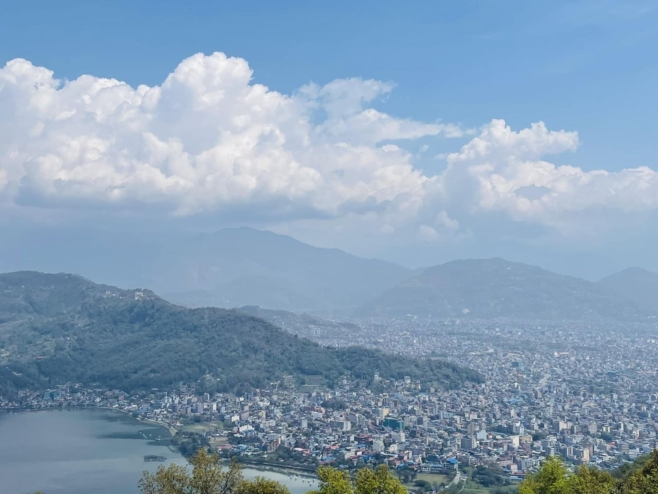 Panoramic view of a city with mountains in the background under a cloudy sky.