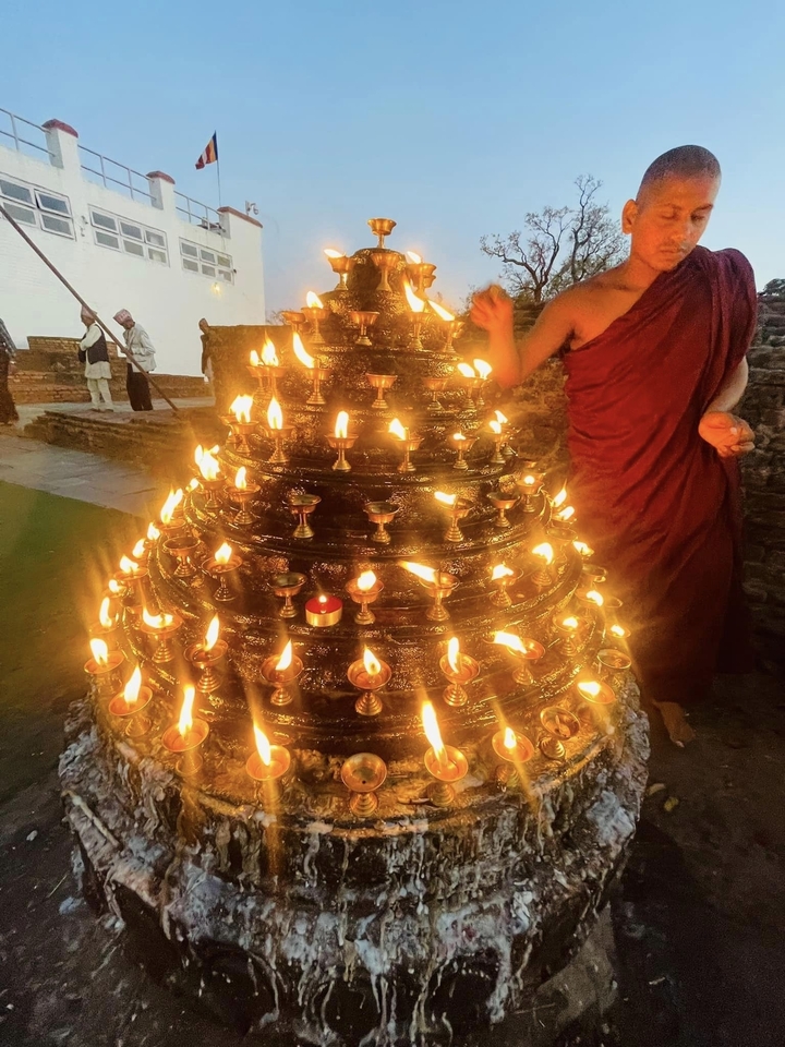 Temple candles lit at night with a person passing by.