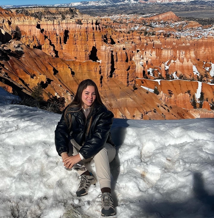 Person sitting in snowy landscape with Bryce Canyon in the background.