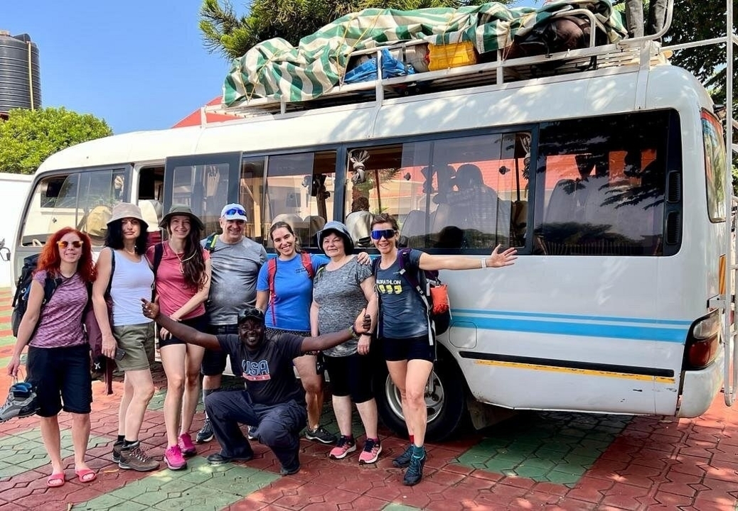 Groupe de touristes posant devant un autocar avec des bagages sur le toit.