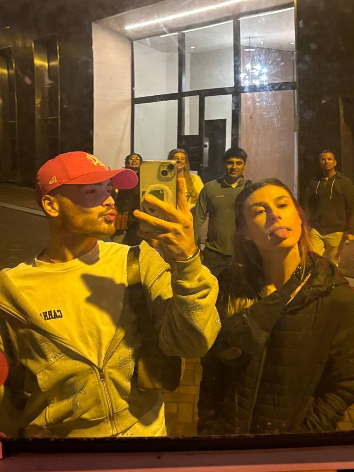 Des gens prenant un selfie avec reflet la nuit.