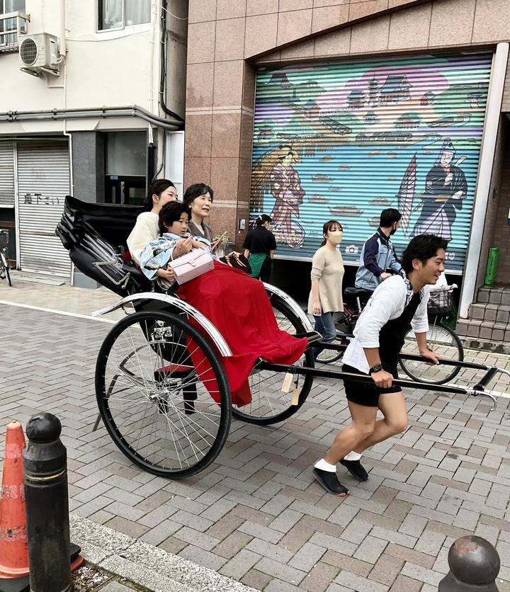 Une personne tirant un pousse-pousse avec des passagers sur une rue pavée.