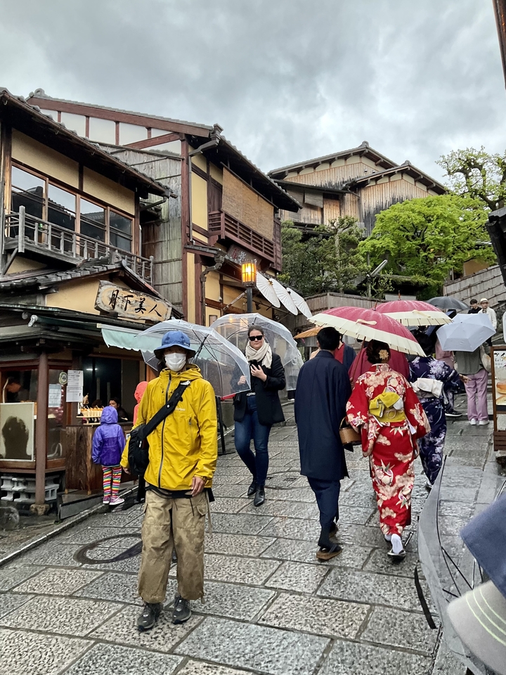 Un groupe de personnes avec des parapluies remontant une rue traditionnelle japonaise.
