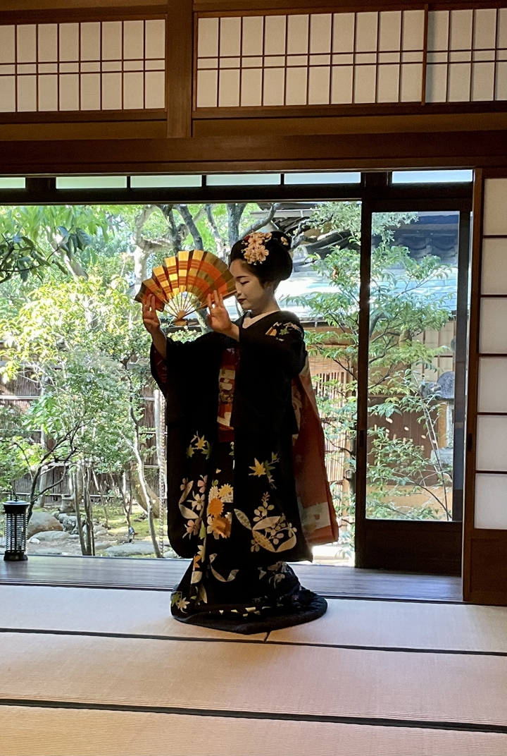 Une personne en costume traditionnel exécutant une danse japonaise traditionnelle à l'intérieur.