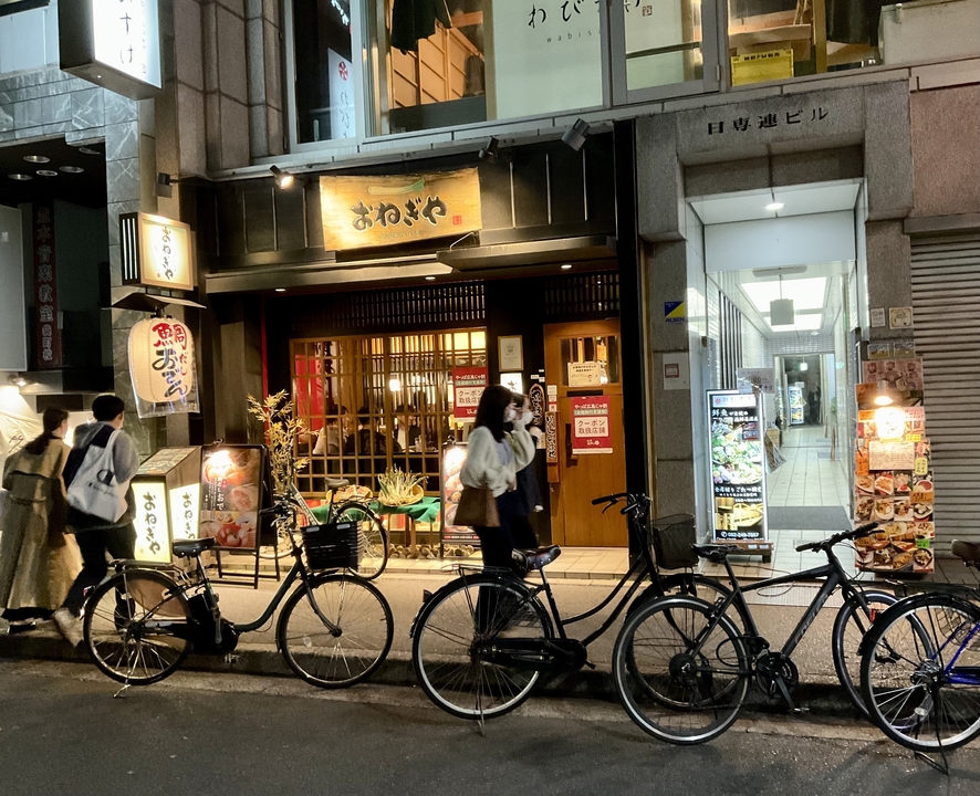 Vélos garés devant un restaurant de rue illuminé la nuit.