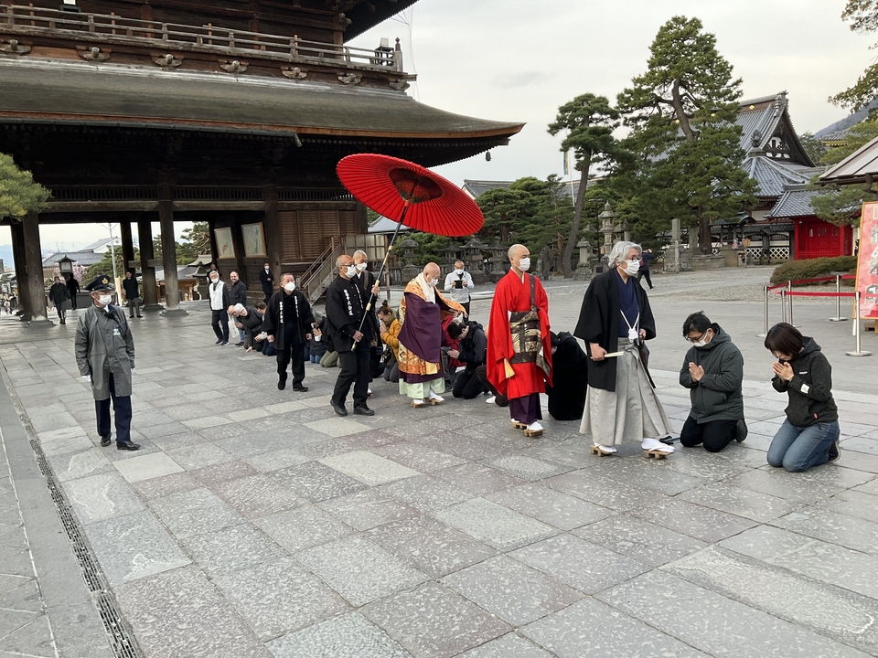 Une procession cérémonielle avec des personnes en vêtements traditionnels à l'entrée d'un temple.