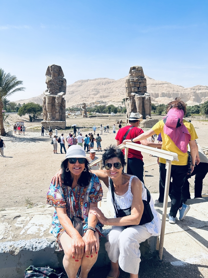 Deux femmes posant devant des ruines antiques avec des statues.