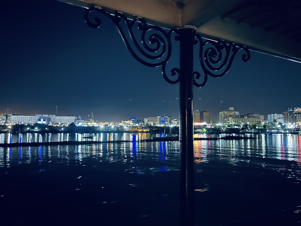 Vue nocturne d'un horizon urbain avec des lumières se reflétant sur l'eau.