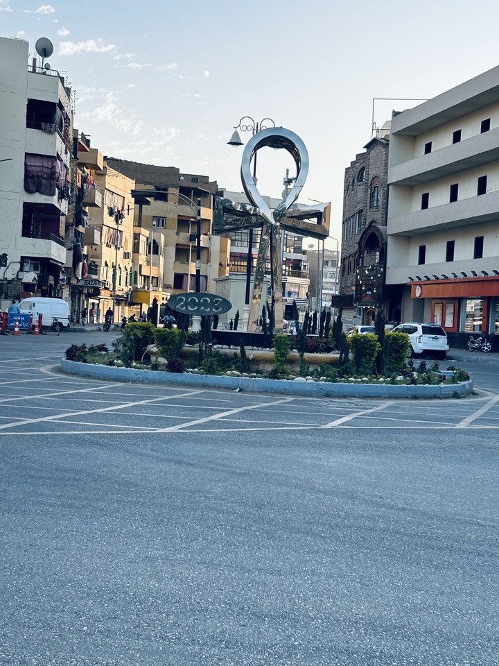 Scène de rue urbaine avec rond-point et voitures garées.
