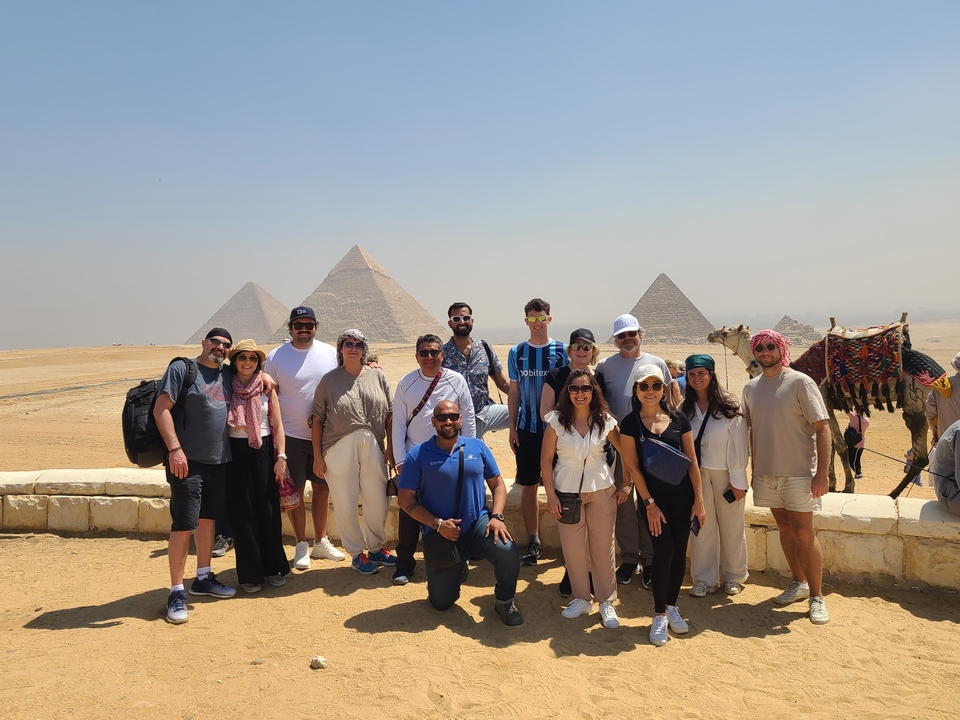 Groupe de touristes posant devant les pyramides de Gizeh.