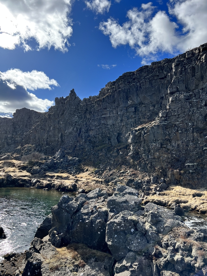 Rocky cliffs under a partly cloudy sky.