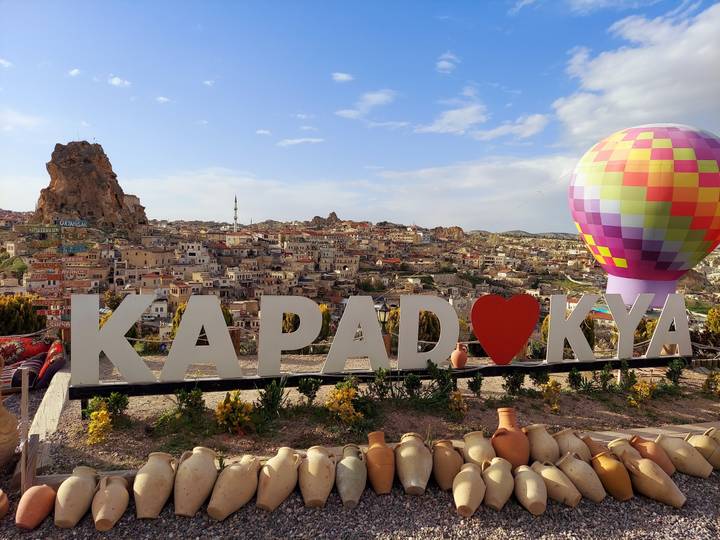 Vue panoramique de la Cappadoce avec une montgolfière colorée.