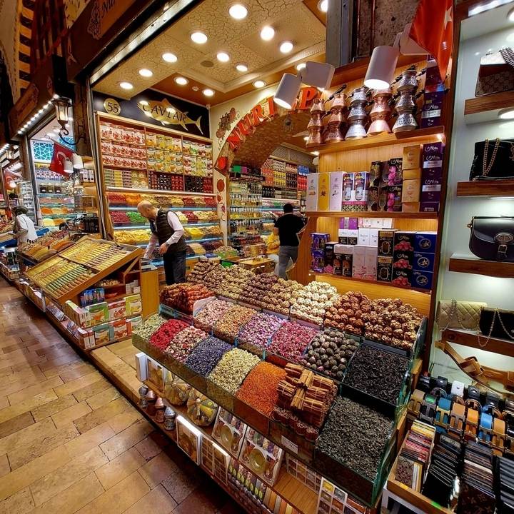 Étal de marché avec des épices colorées et des marchandises exposées.