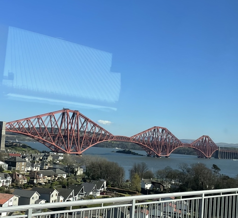 Grand pont ferroviaire rouge enjambant une étendue d'eau.