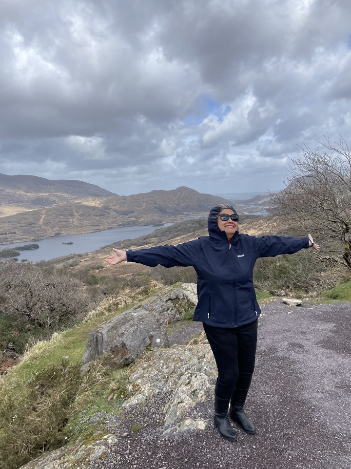 Personne aux bras étendus dans un paysage montagneux.