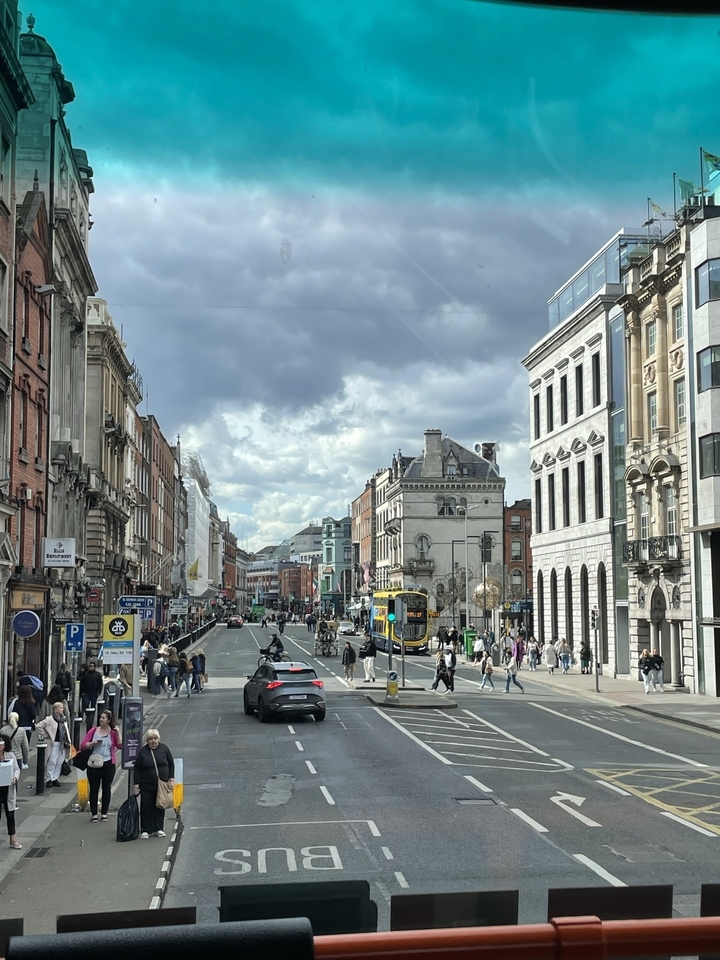 Rue animée de la ville avec des bâtiments historiques et un bus public.