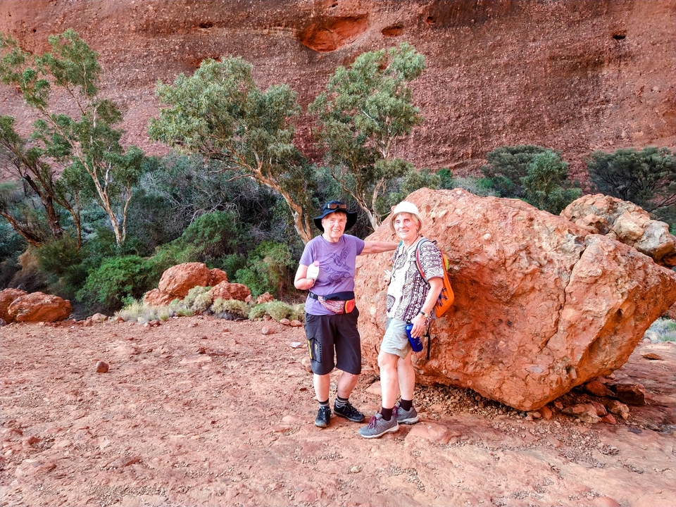 Deux personnes posant devant une grande formation rocheuse.