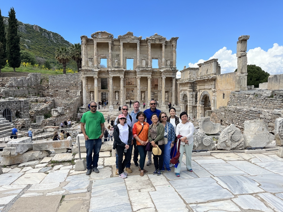 Groupe de touristes posant devant une ruine historique.