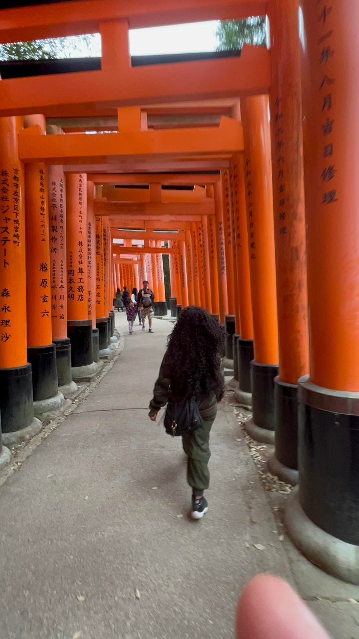 Des touristes marchant à travers les célèbres portiques orange d'un sanctuaire.