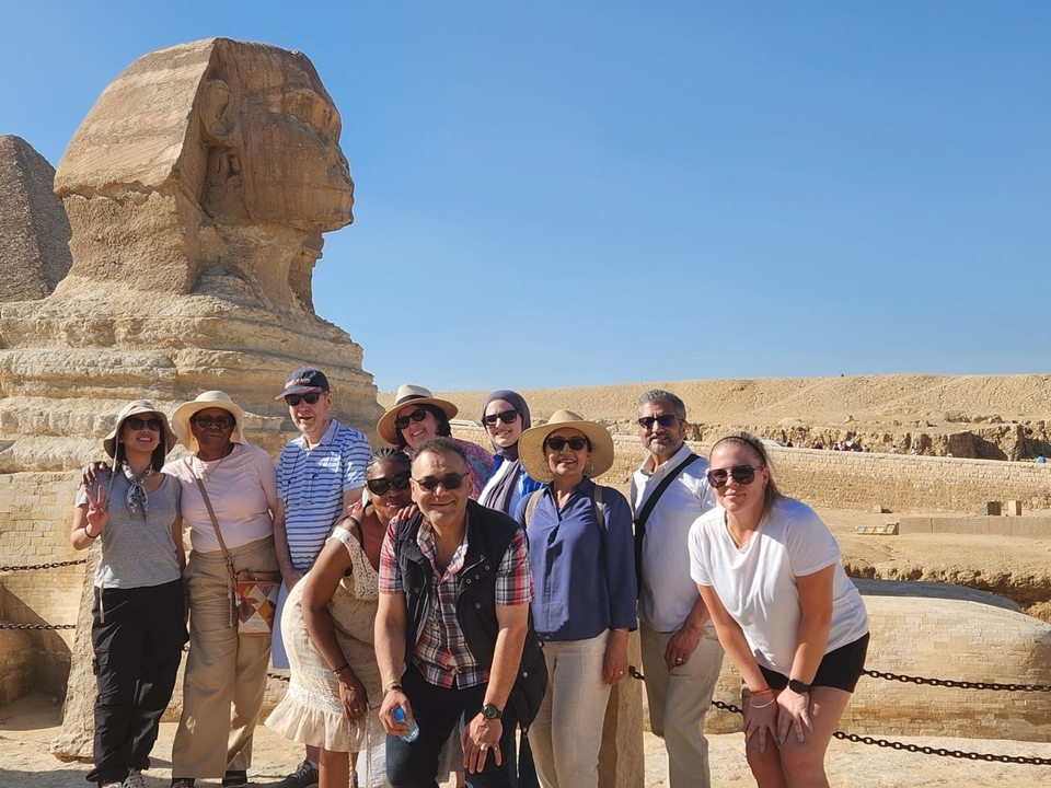 Groupe de touristes prenant la pose devant le Grand Sphinx de Gizeh.