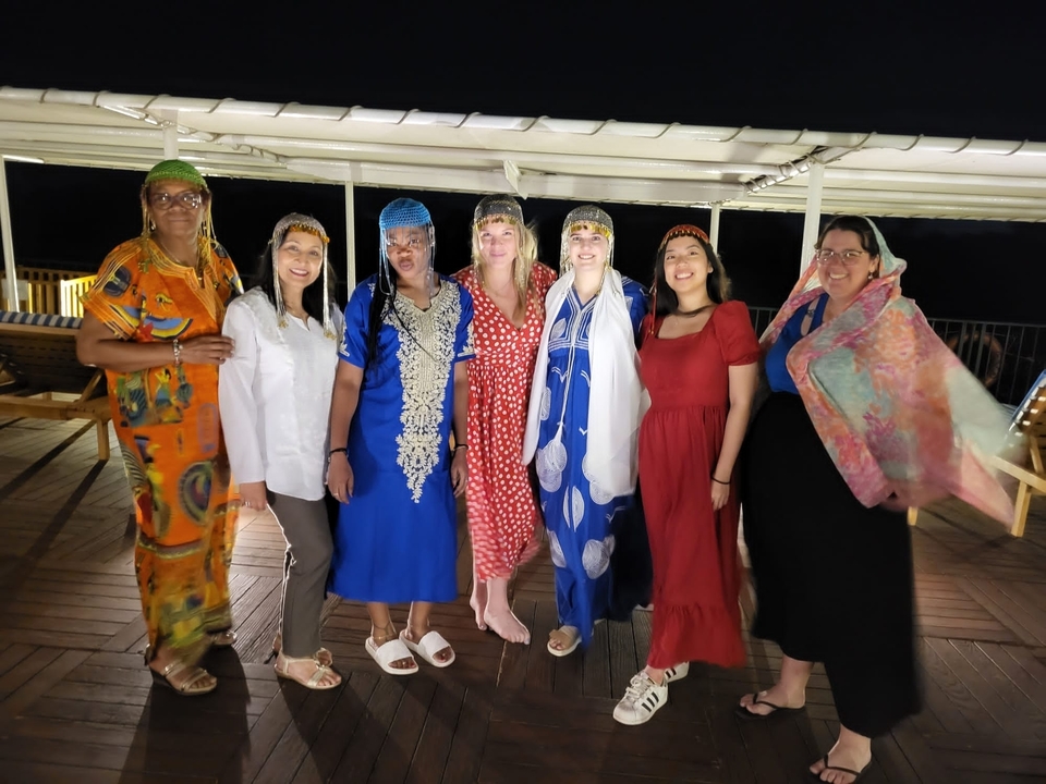Groupe de personnes vêtues d'habits traditionnels sur un bateau la nuit.
