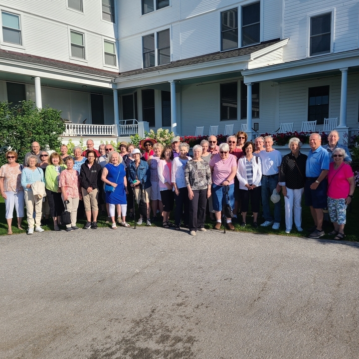 Groupe de personnes se rassemblant devant un grand bâtiment pour une photo de groupe.