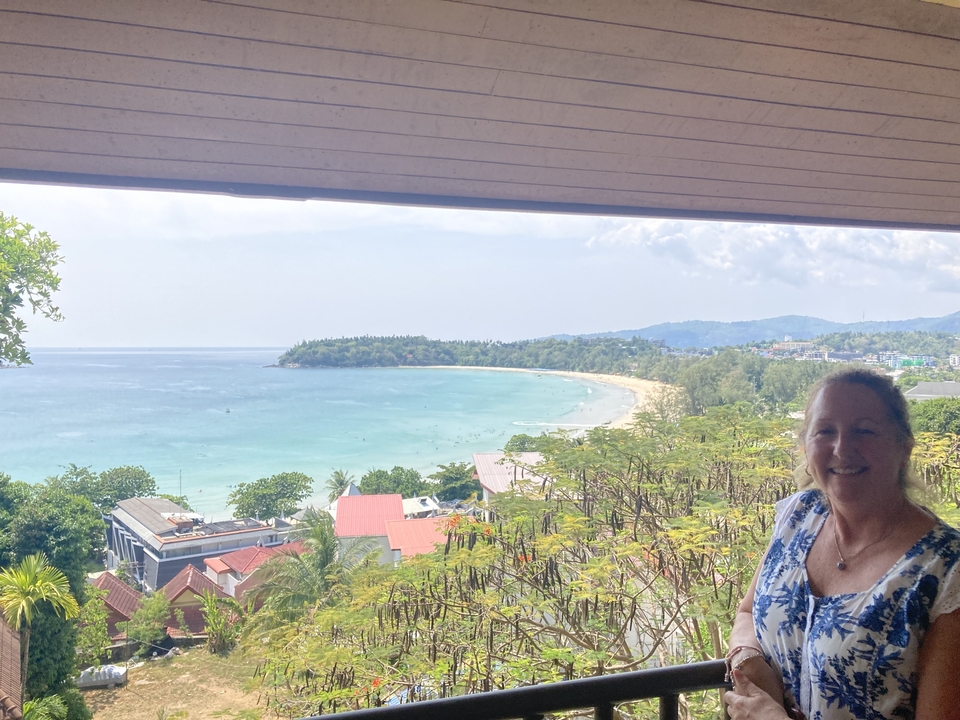 Vue depuis un balcon donnant sur une plage avec une personne souriante.