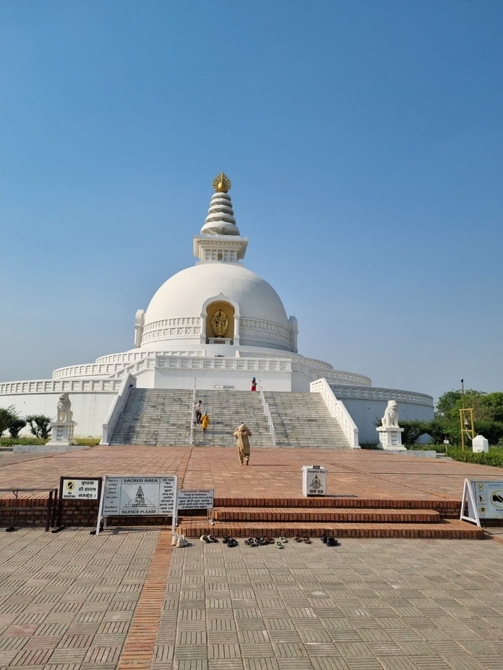 Large white stupa with visitors walking up the steps.