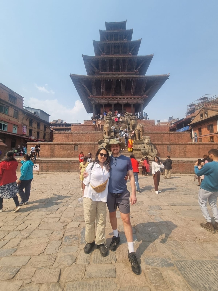 Couple posing in front of a historic temple with statues.