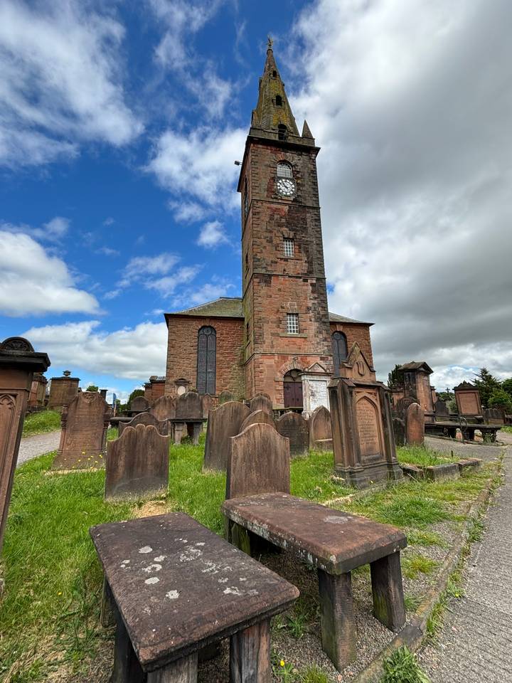 Een historische kerk met een kerkhof onder een blauwe hemel.