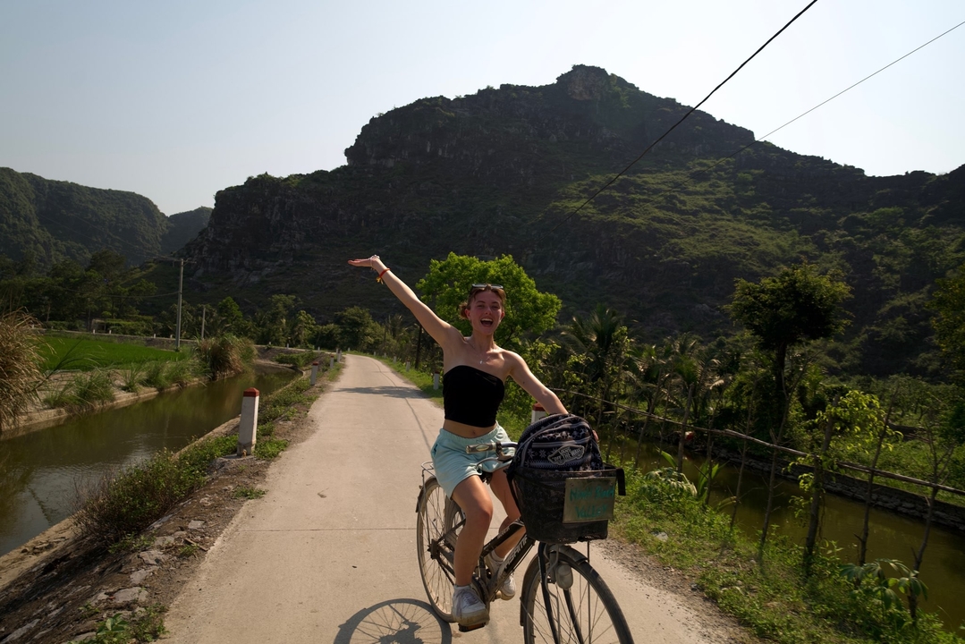 Personne sur un vélo levant un bras avec des collines en arrière-plan.
