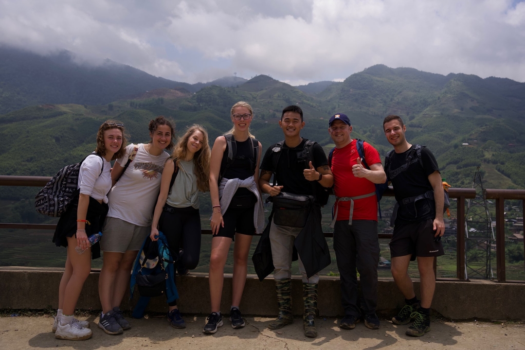 Groupe de personnes posant avec des montagnes en arrière-plan.