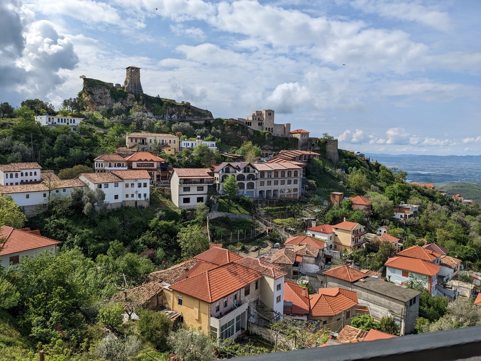 Village de colline avec une forteresse historique et des maisons aux toits rouges.